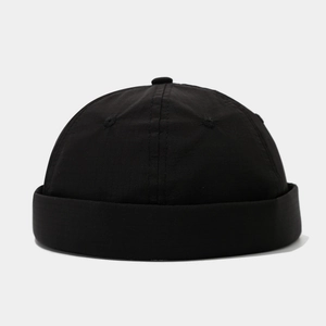 Macro detail of breathable black docker cap showing woven fabric texture and stitching