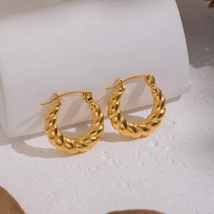 Close-up of gold twist hoop earrings with textured metal finish and high-shine luster