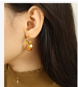 Close-up of golden stainless steel earrings with irregular lava and crinkle texture