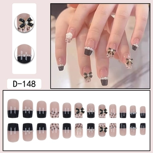 Short pink press-on nails with black French tips, 3D bows, and camellia floral charms