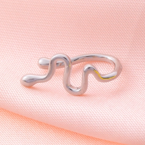 Close-up of liquid metal style wavy silver cuff on pink textured fabric background