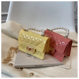 Detail of yellow and coral silicone jelly bags with pearl handles and gold hardware