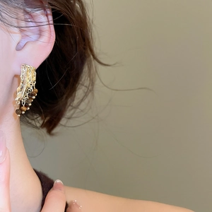 Détail de boucles d'oreilles dorées à pampilles avec perles brunes sur mannequin