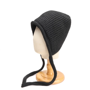 Dettaglio del cappello di lana nera con lacci lunghi e trama a maglia spessa rifinita