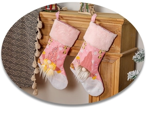 Calze natalizie rosa luminose con gnomo e paillettes appese al caminetto