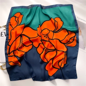 Detail of floral silk square scarf featuring orange lilies and color-block stitching