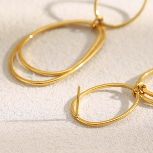 Detail view of double-hoop 18K gold plated stainless steel earrings with glossy finish