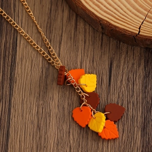 Detail of autumn maple leaf necklace with gold chain on rustic wooden background