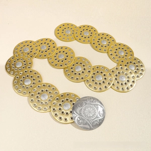 Detail of bohemian metal disc belt with ornate floral engraved silver buckle and gold plates