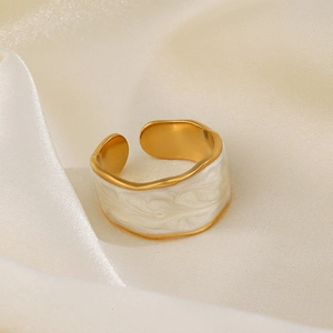 Anello a onda placcato in oro con smalto bianco su elegante tessuto di raso beige