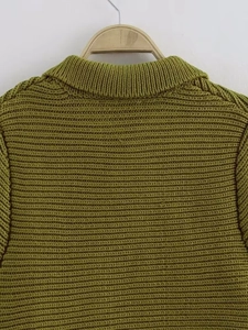 Close-up of green chunky knit sweater showing rib neckline and premium wavy texture