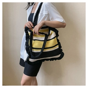 Detail of hand-woven striped tote bag with elegant black ruffled edges on shoulder