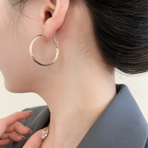 Polierter goldener geometrischer Creolen-Ohrring, getragen im minimalistischen Stil