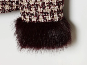 Detail of tweed blazer fabric with faux fur cuffs in wine red and black weave