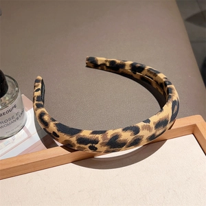 Detailed view of leopard print fabric headband displayed on a vintage wooden frame
