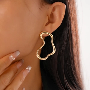 Close-up of woman wearing a large gold irregular wavy hollow earring with metallic finish