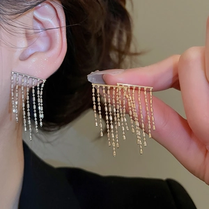 Detail of long metal tassel earrings with delicate bead chain design in gold and silver