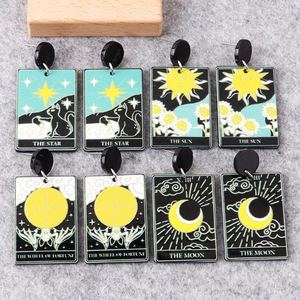 Macro view of Tarot card earrings featuring sun and star prints on acrylic material