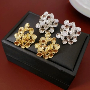 Macro shot of gold and silver flower cluster stud earrings on a black jewelry box