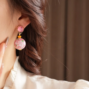 Détail de boucles d'oreilles vintage en céramique rose portées par un mannequin