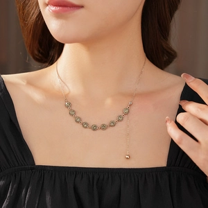 Close-up of a French style gold bead necklace with dark gemstone on a female model