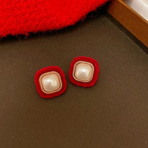 Macro detail of red velvet square earrings with pearl inlay and gold twisted metal frame