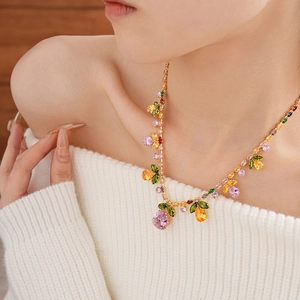 Close-up of golden necklace with colorful pear-shaped zircon stones and leaf accents