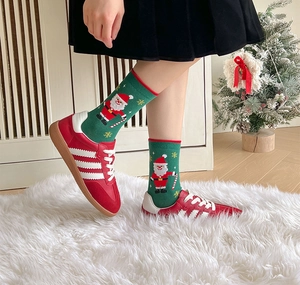 Detail of green knitted Christmas socks with Santa Claus pattern worn in a cozy home setting