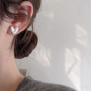 Minimalist silver irregular heart stud earrings shown on model with natural lighting
