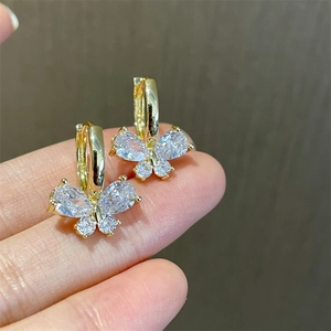 Detailed view of gold butterfly hoop earrings with sparkling cubic zirconia held by hand