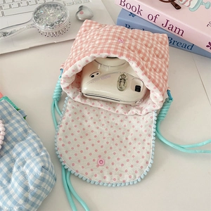 Detail of pink plaid quilted camera bag with soft blue pom-poms and polka dot lining