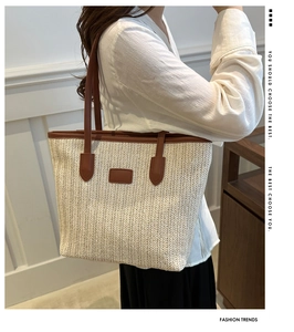 Detail of handwoven straw tote bag with brown leather handles and rectangular patch