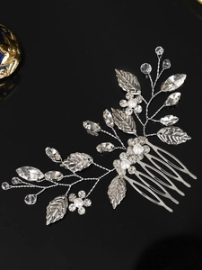 Macro view of silver bridal hair comb with alloy leaves, crystals and faux pearls