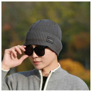 Detail of dark grey knit beanie with IFARDI patch and ribbed texture on a model