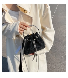 Close-up of black bucket bag with sparkling rhinestones, ring handle and chain fringe