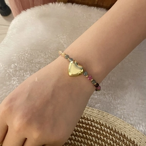 Retro natural stone beaded bracelet with heart pendant shown on model in warm lighting