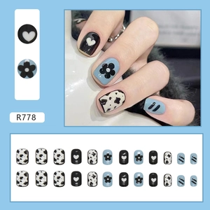 Short square press-on nails featuring cow print and heart patterns in black, blue and white