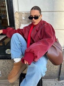 Street style shot of a woman in a red leather jacket, jeans, and brown platform boots