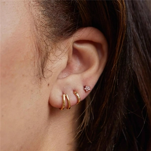 Close-up of S925 silver gold-plated cross star hoop earrings worn on ear lobes