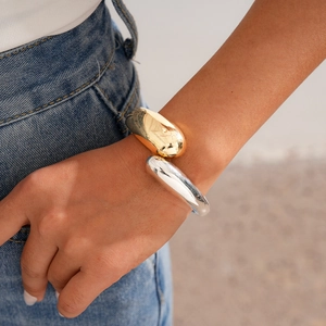 Polished gold and silver mixed metal geometric bangle bracelet on wrist with a minimal design