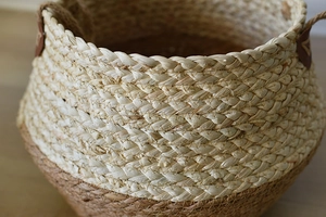 Close-up of dual-tone handwoven grass flower basket with brown leather handles