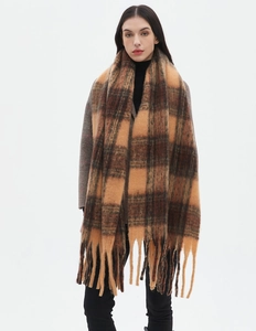 Detail of soft brown plaid scarf with fringe tassels shown on a model in studio lighting