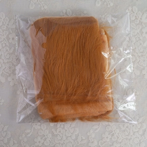 Detail view of plush lion ear headband in clear plastic packaging on white lace