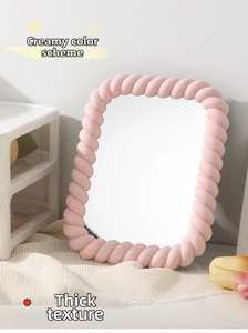 Detail of a pink cream-style vanity mirror with an adjustable rope-patterned frame