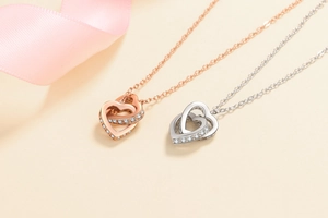 Détail de pendentifs cœurs entrelacés en or rose et argent avec accents de zircons