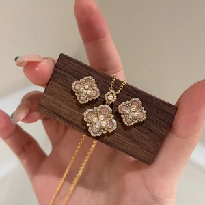 Detail of flower necklace and earrings with pink stones and white pearls on wood
