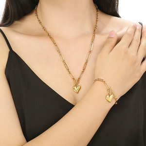 Ensemble collier et bracelet dorés avec pendentifs cœur portés par un mannequin
