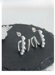 Macro detail of double-layer titanium earrings with white pearls and Czech crystals