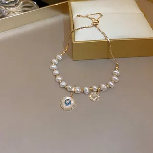 Gold-plated pearl bracelet with cat eye stone, flower charms, and adjustable sliding clasp