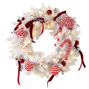White flocked Christmas wreath with red bows, candies, and warm LED lights on white background